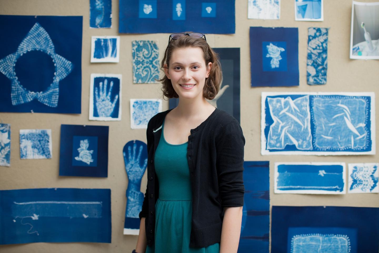 photo of artist Sasha Faust st和ing in front of some of her works
